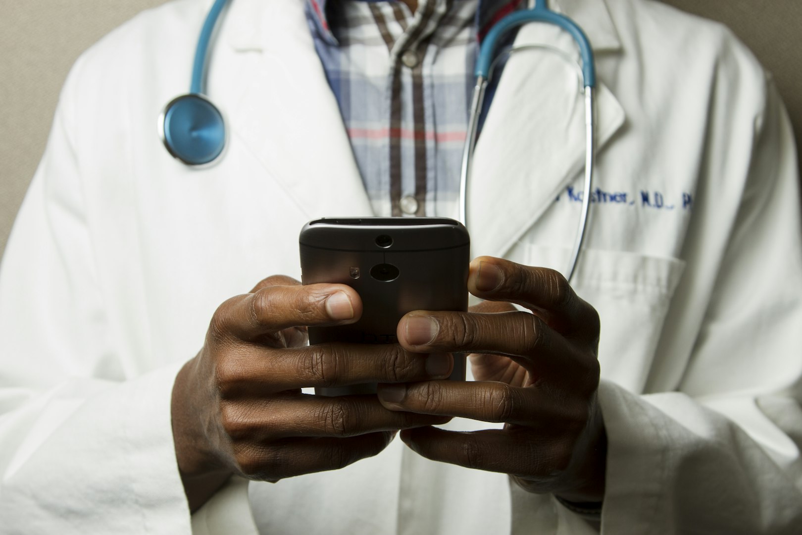 A clinician with a stethoscope using a handheld device